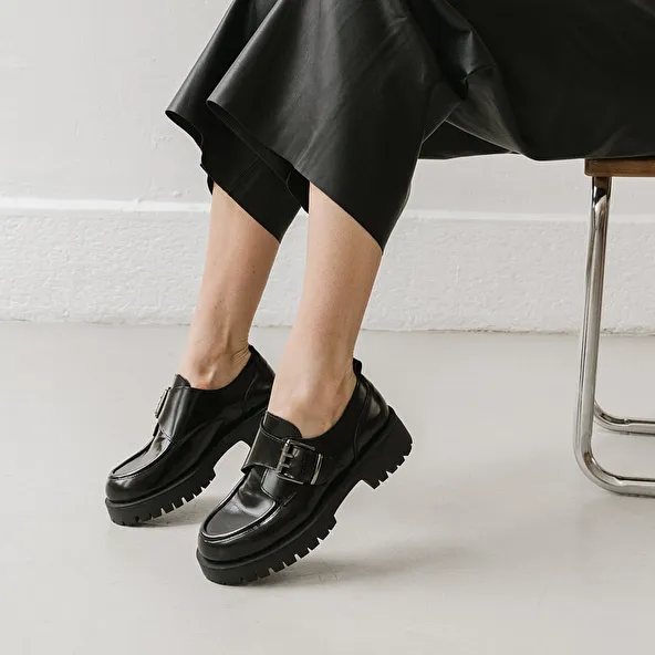 Derbies with flat heels, buckles and visible seams in black shiny leather